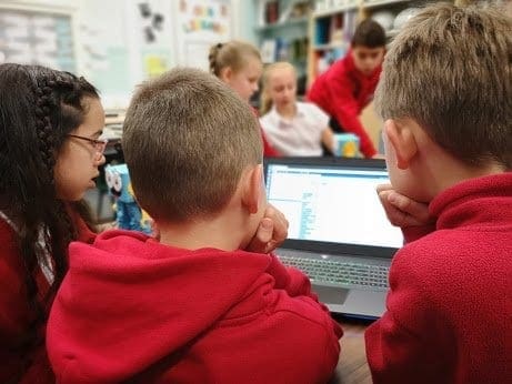 Some students around a laptop writing code with Marty the Robot